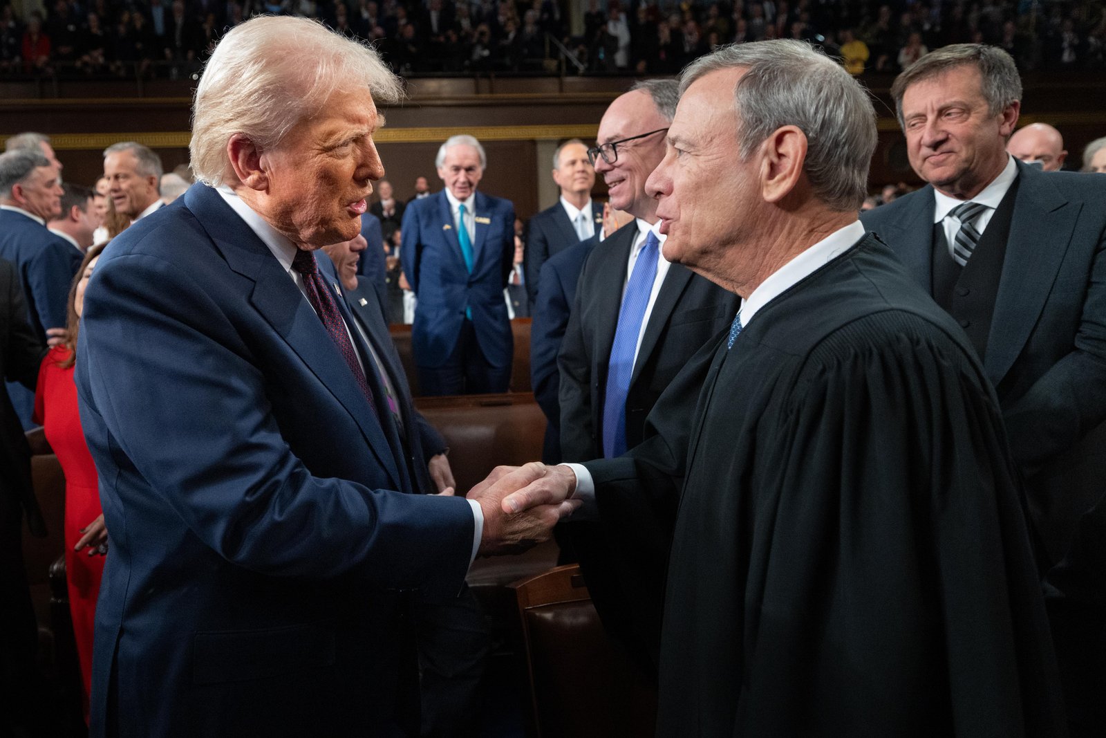 Roberts and Trump shake hands and look quite jovial.