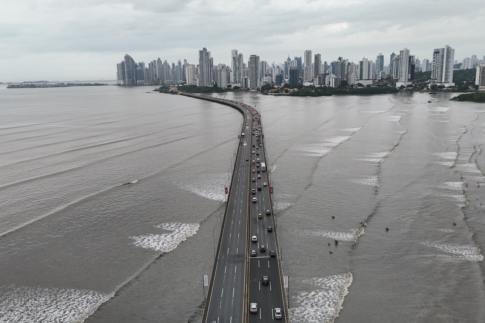 Cars are at a standstill along the Pan-American Highway in Panama City, beneath which waves can be seen rolling with low white caps
