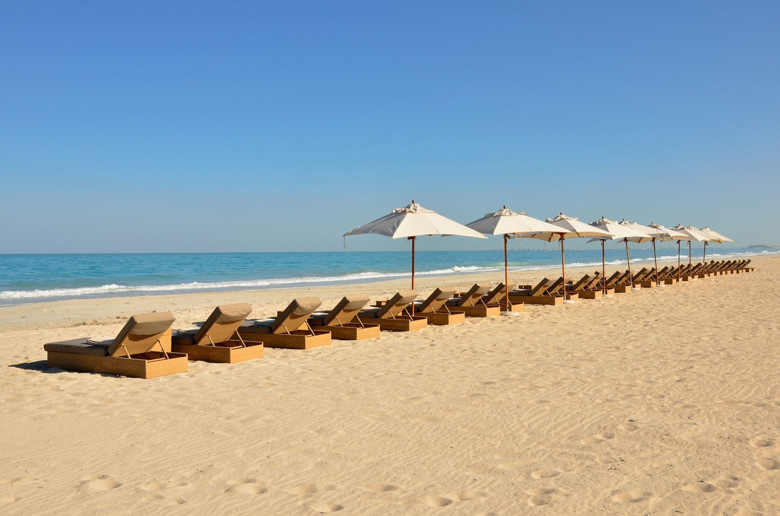 Sunbeds and sunshades on the beach of the Park Hyatt hotel on Saadiyat Island, Abu Dhabi, United Arab Emirates.