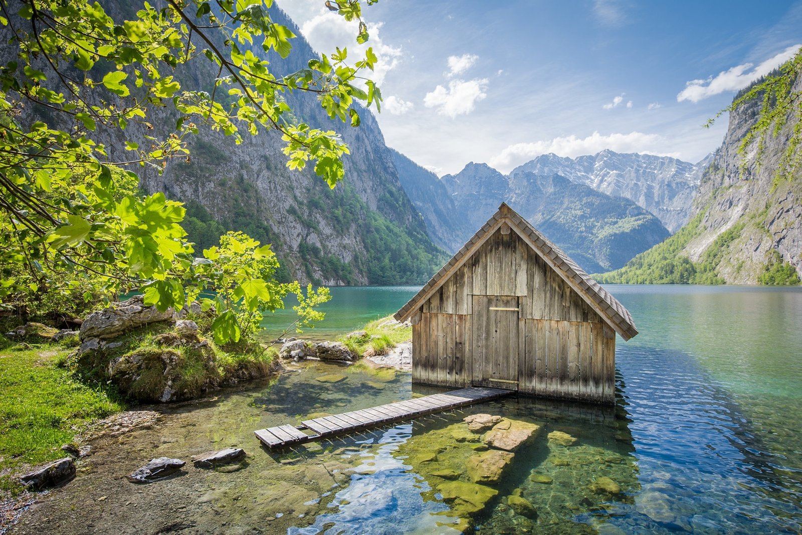 A wooden hut on the side of a sunny Lake Constance.