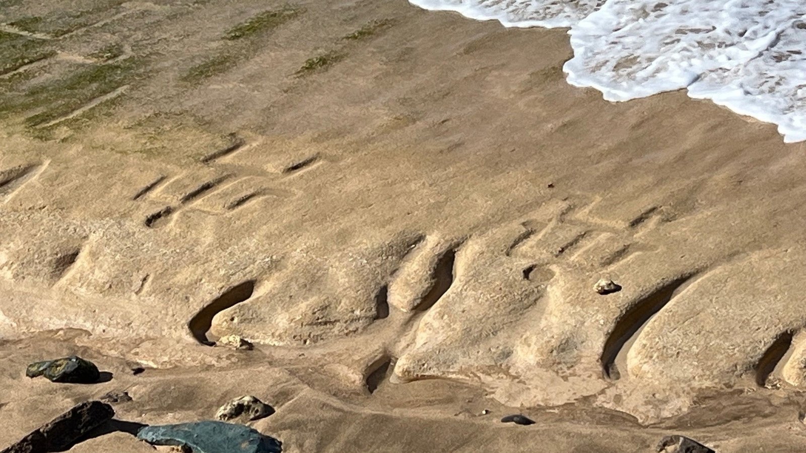 Hawaiian petroglyphs on sandstone beach with tidal wave