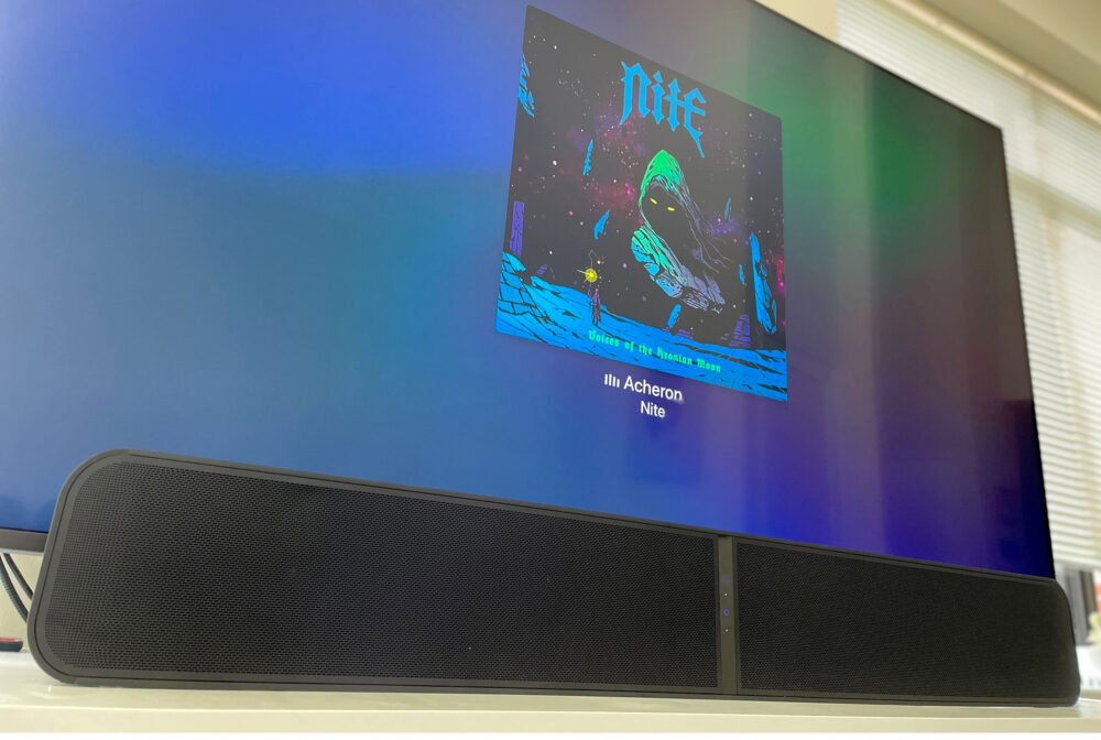 Bluesound PULSE SOUNDBAR+ in front of TV displaying Apple Music