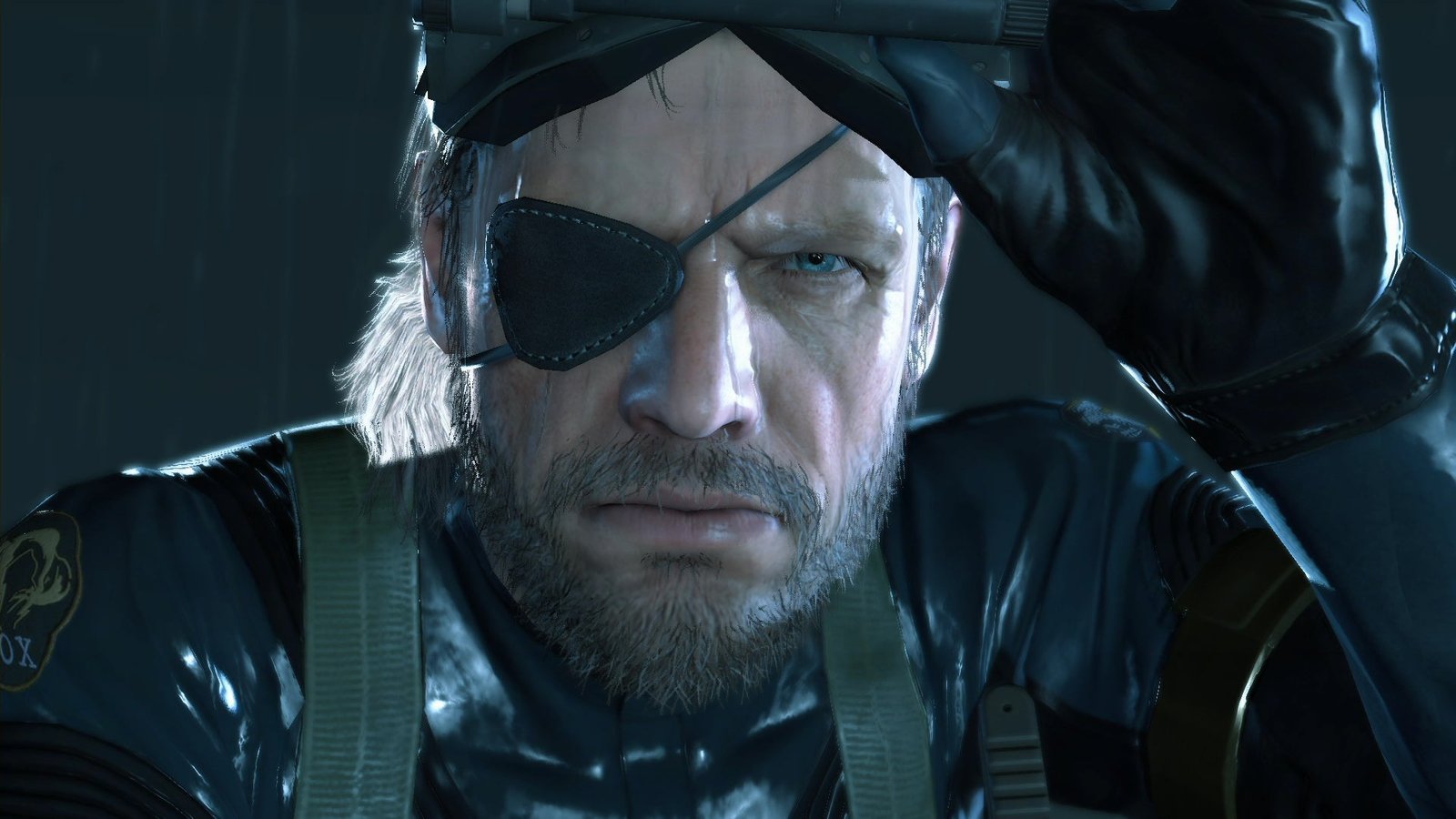 A close-up of the eye-patch-wearing protagonist of Metal Gear Solid: Ground Zeroes, with a grizzled beard and body armour.
