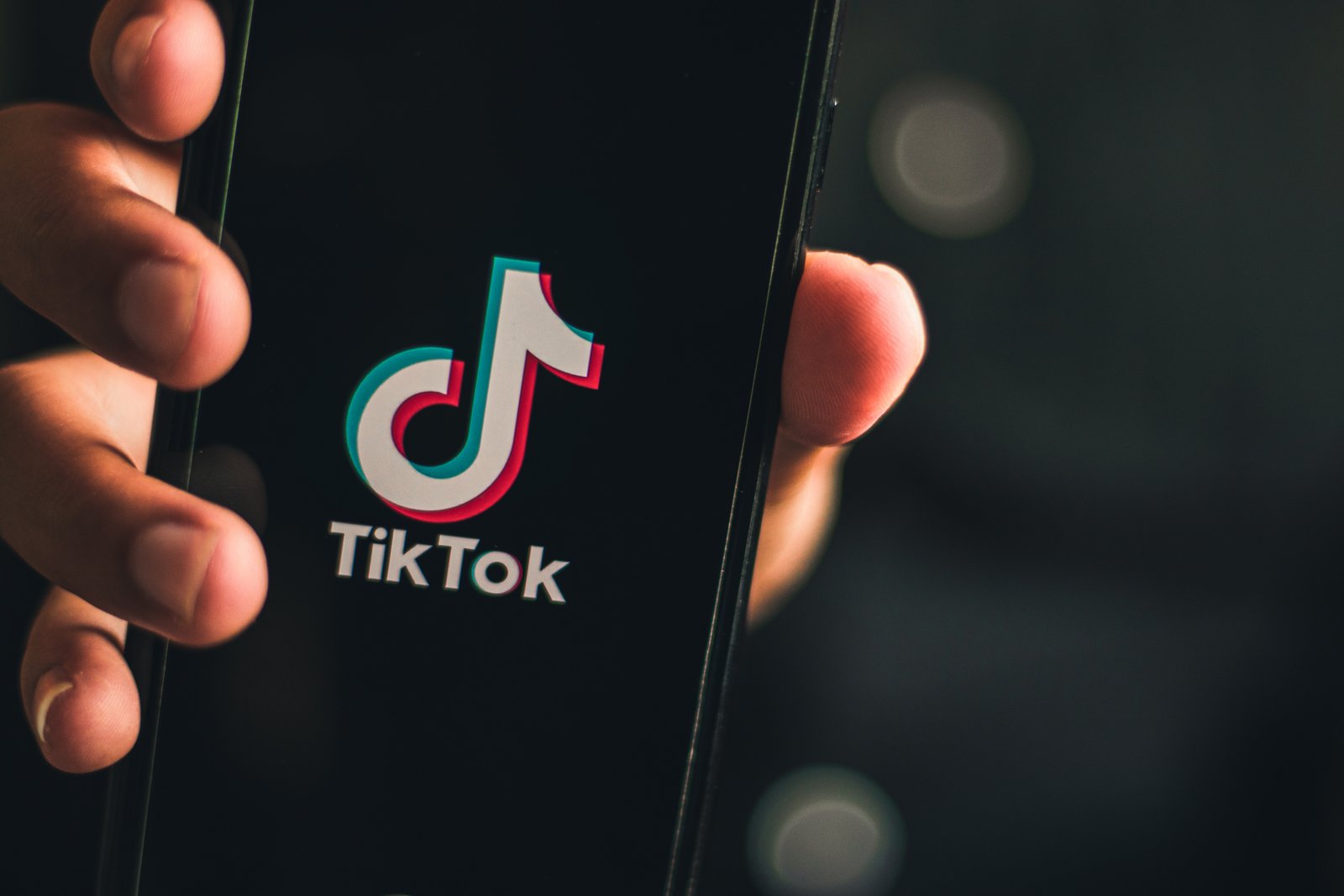 Hand holding smartphone displaying the TikTok logo.