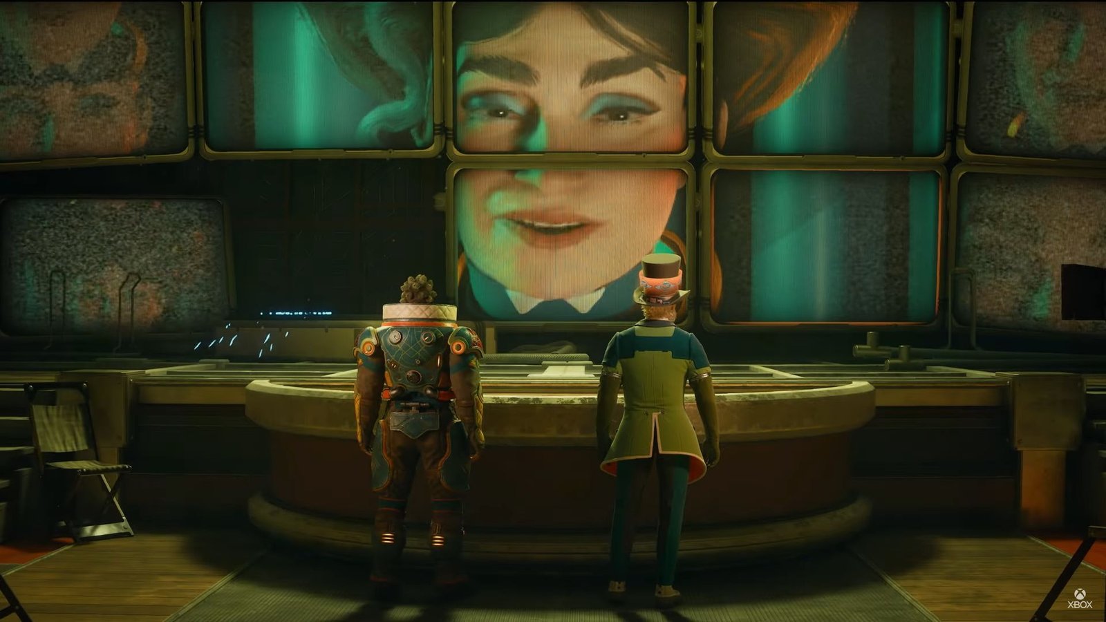 Two soldiers consult a bank of screens on which their motherly CEO gives orders.