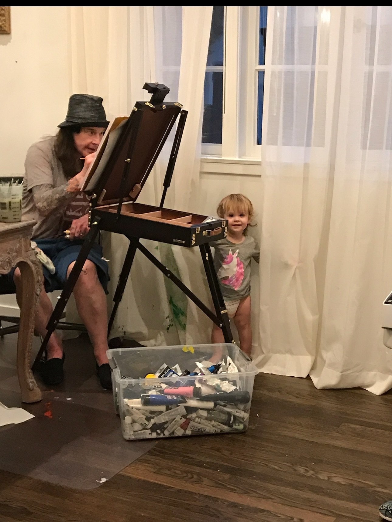 Ozzy Osbourne paints with a grandchild nearby. 