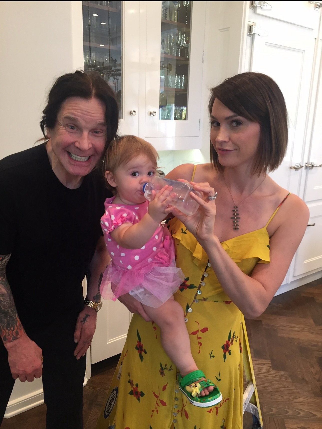 Lisa Stelly holds a baby with Ozzy Osbourne. 