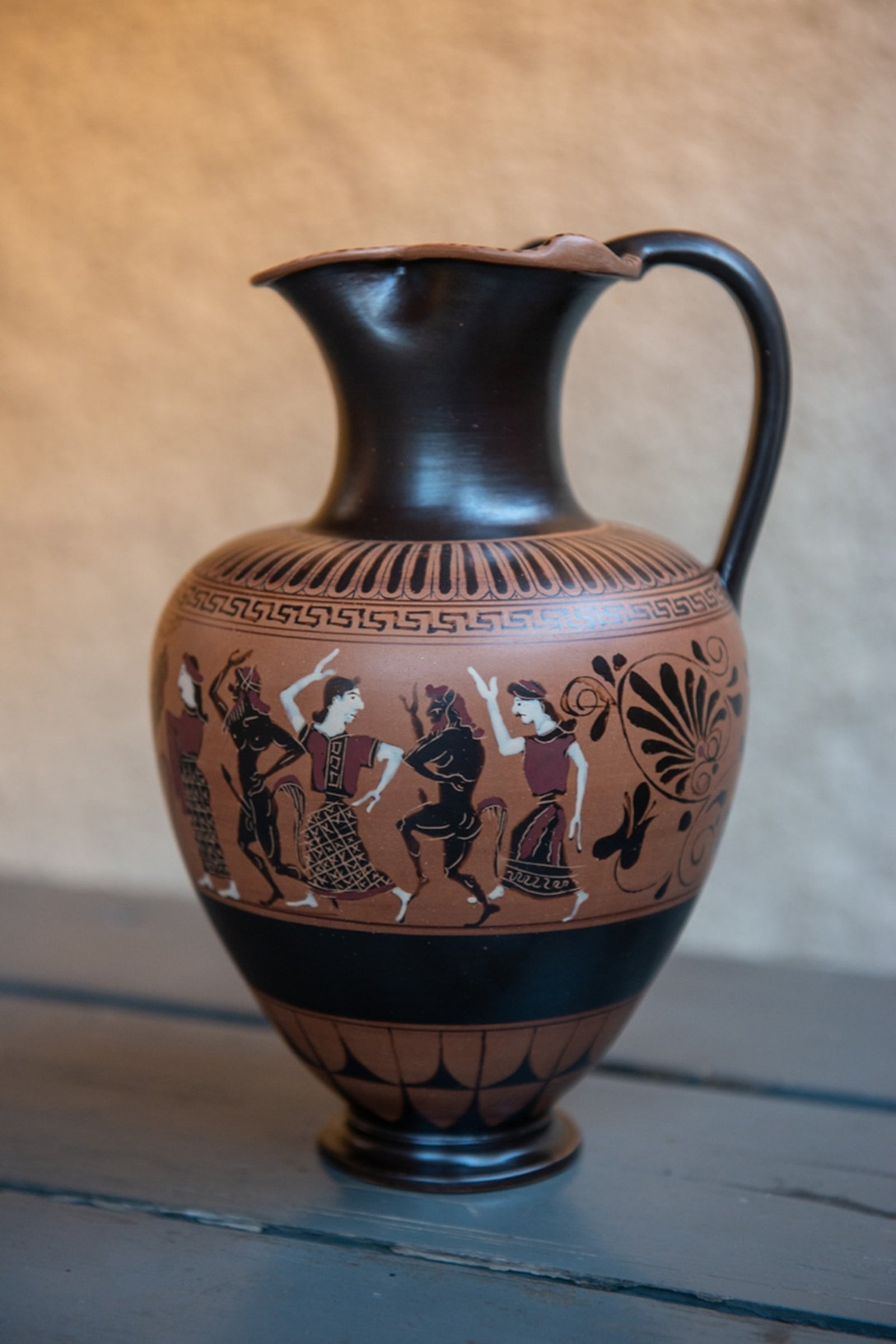 a brown and black jug depicting people