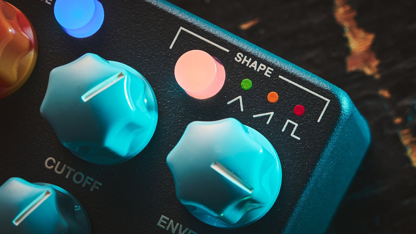 MXR MB301 Bass Synth: the dark gray bass pedal has light blue and orange dials and is photographed here against a distressed wooden background.