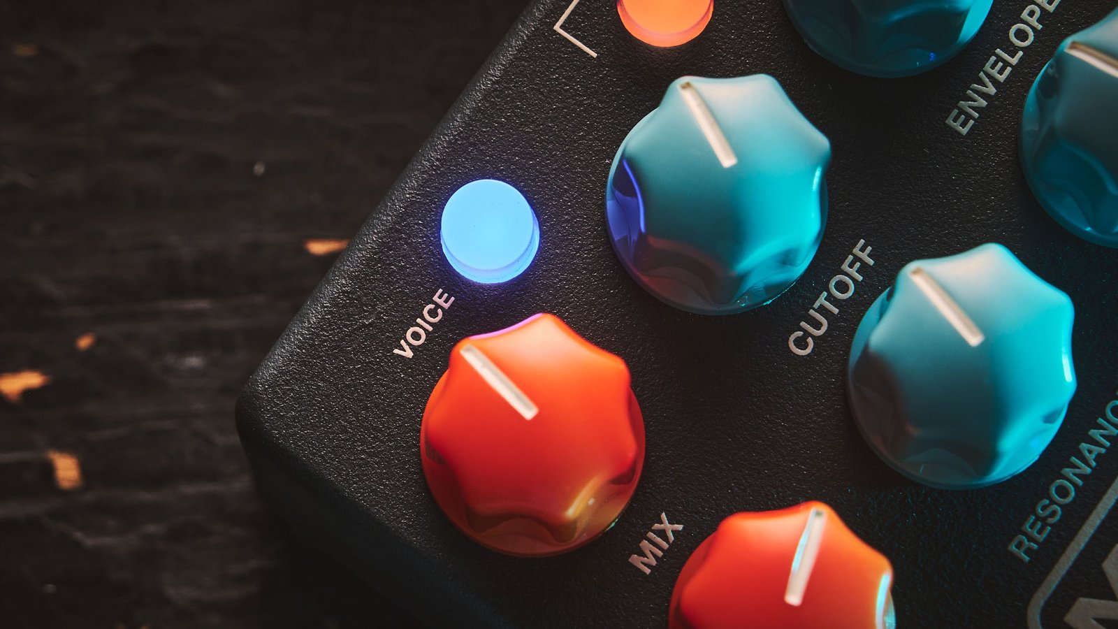 MXR MB301 Bass Synth: the dark gray bass pedal has light blue and orange dials and is photographed here against a distressed wooden background.