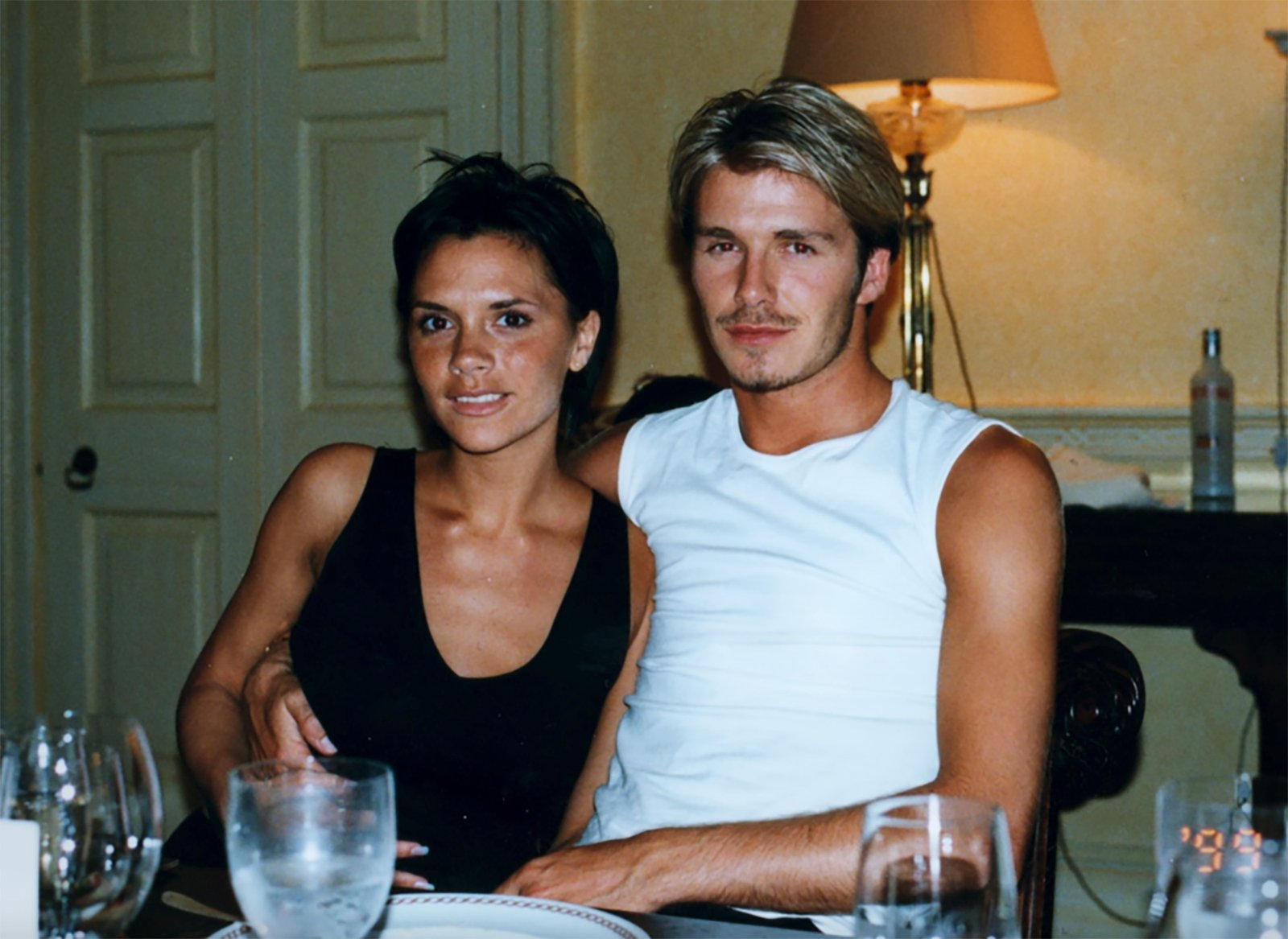 David Beckham in a white tank top, Victoria Beckham in a black top.
