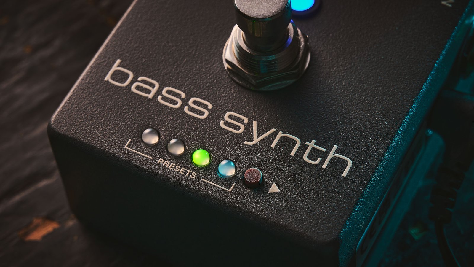 MXR MB301 Bass Synth: the dark gray bass pedal has light blue and orange dials and is photographed here against a distressed wooden background.