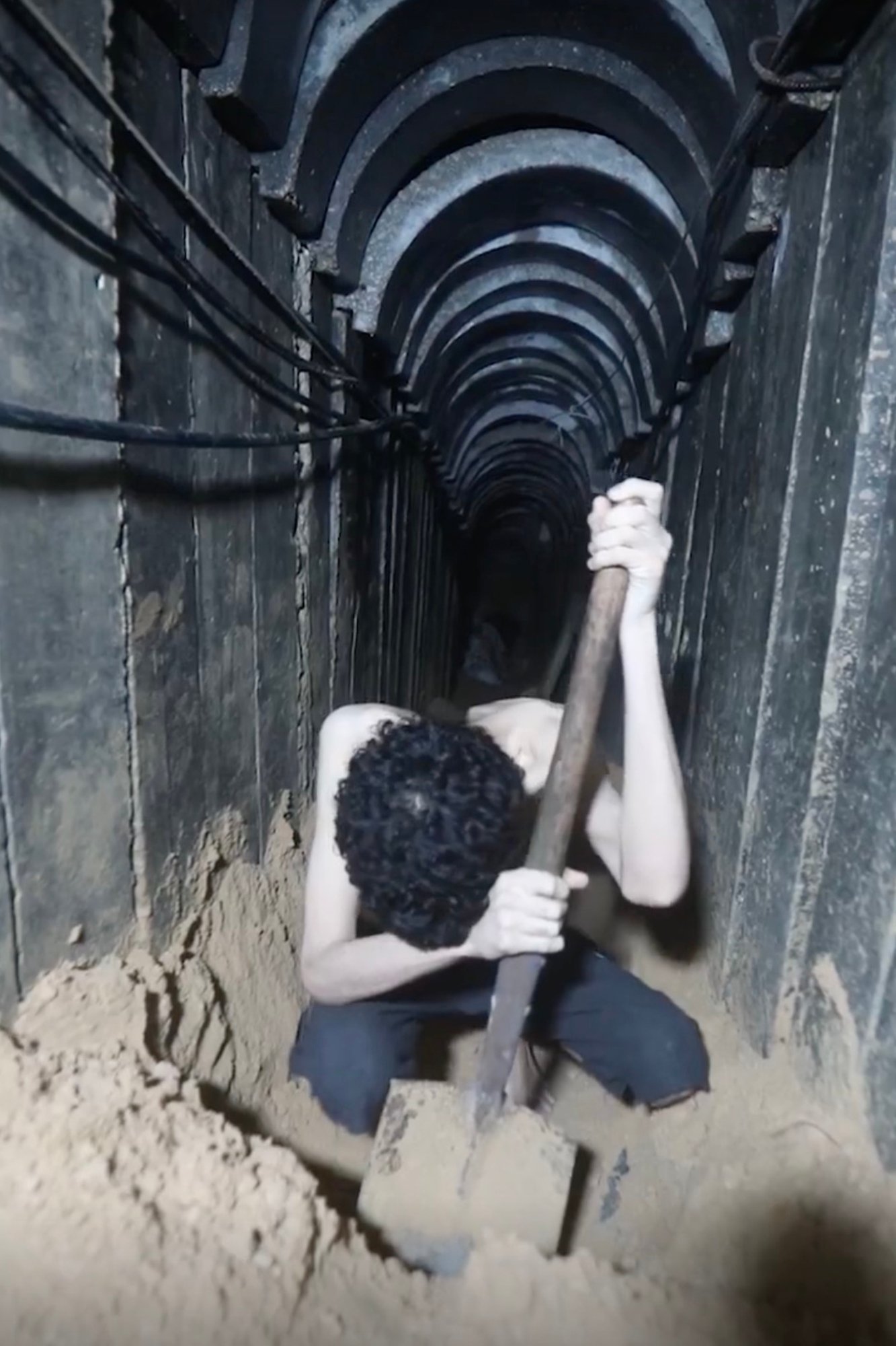 A young man digging in a dark tunnel.