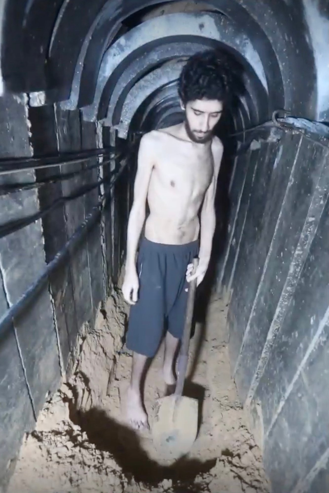 Emaciated hostage digging in a tunnel.