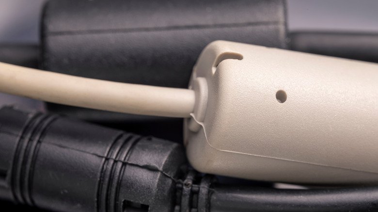 A white cable with a ferrite bead on top of two black cables with ferrite beads