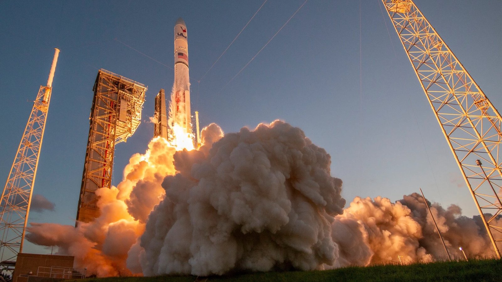 ground-level view of a large white rocket launching into a clear sky