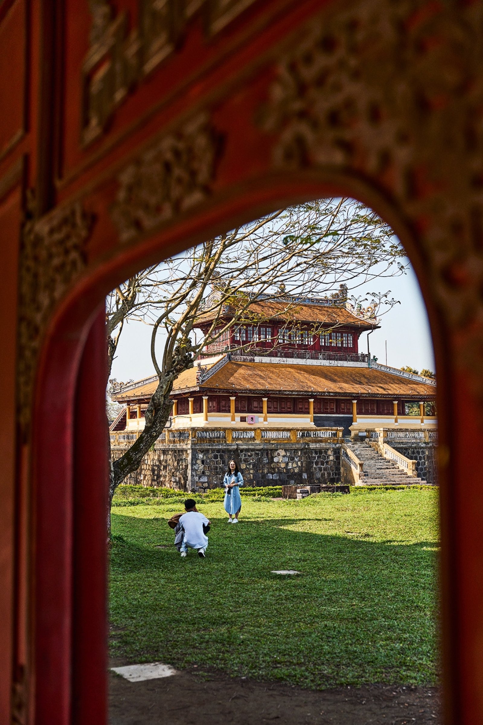 A couple take a photo in front of an old Vietnamese building