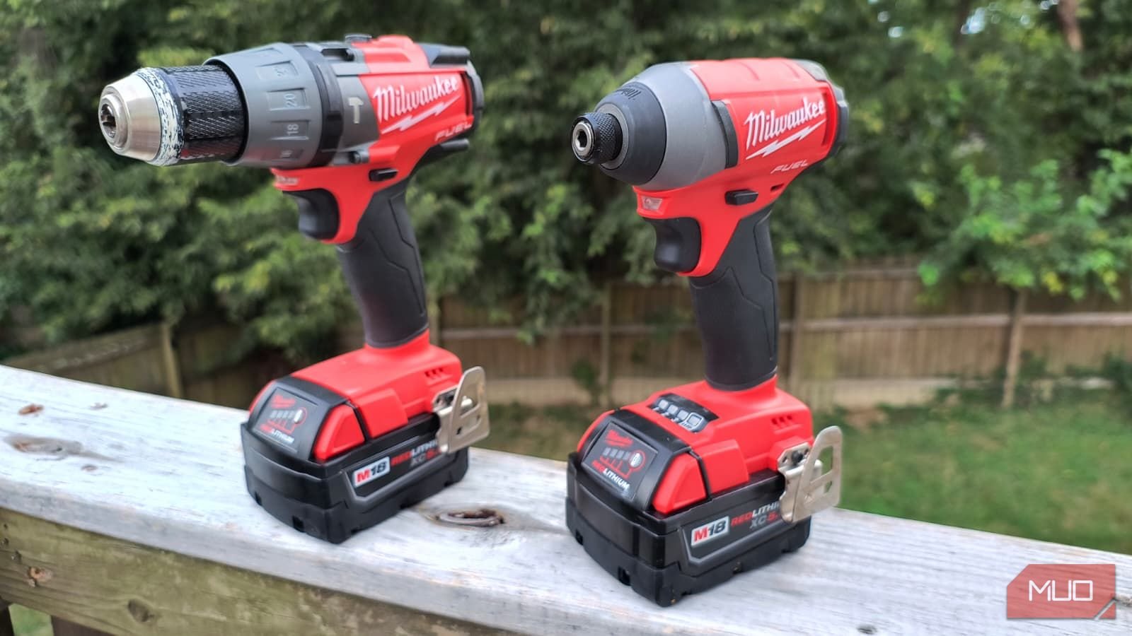 A cordless drill and driver on a wooden rail