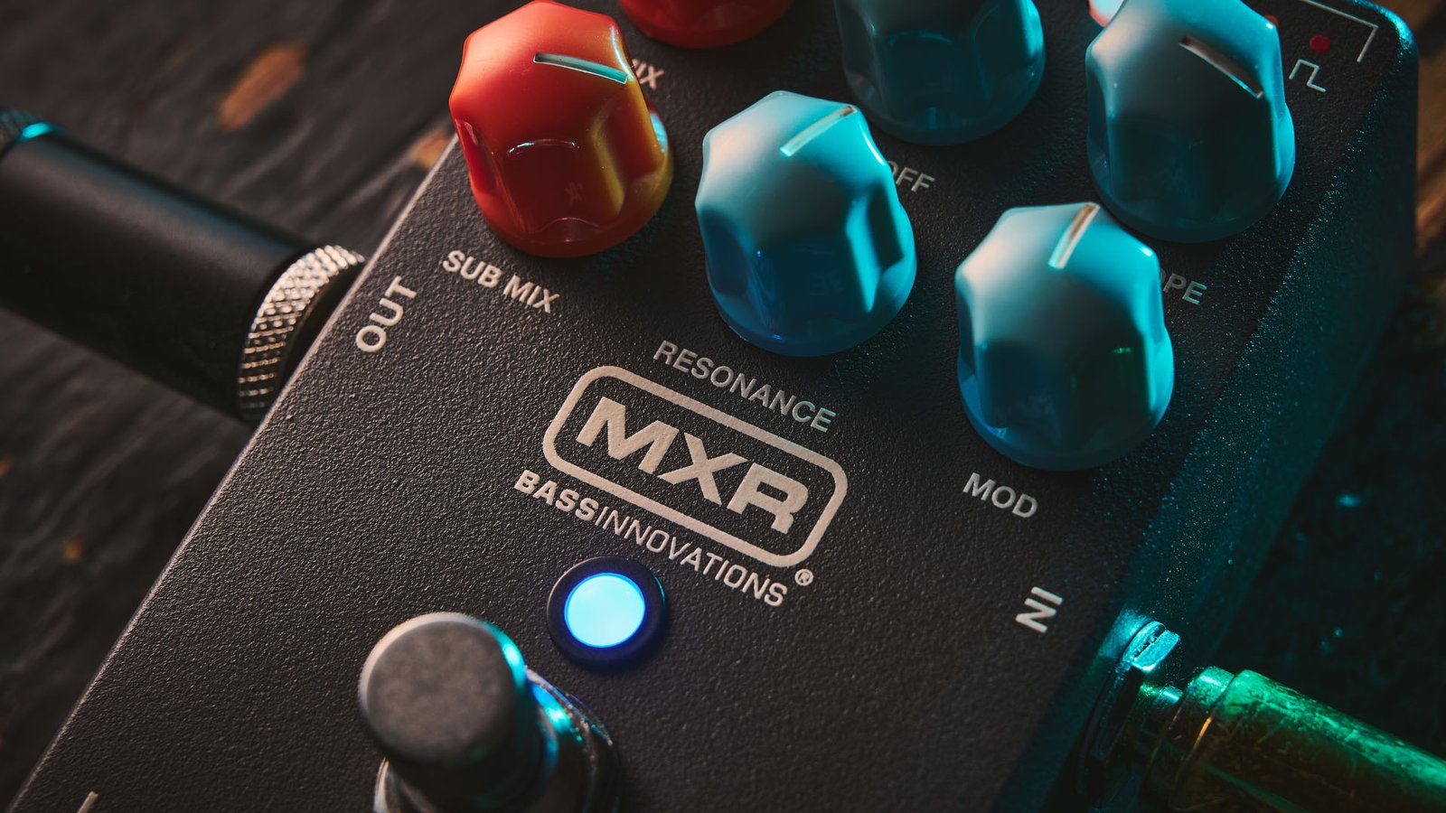 MXR MB301 Bass Synth: the dark gray bass pedal has light blue and orange dials and is photographed here against a distressed wooden background.